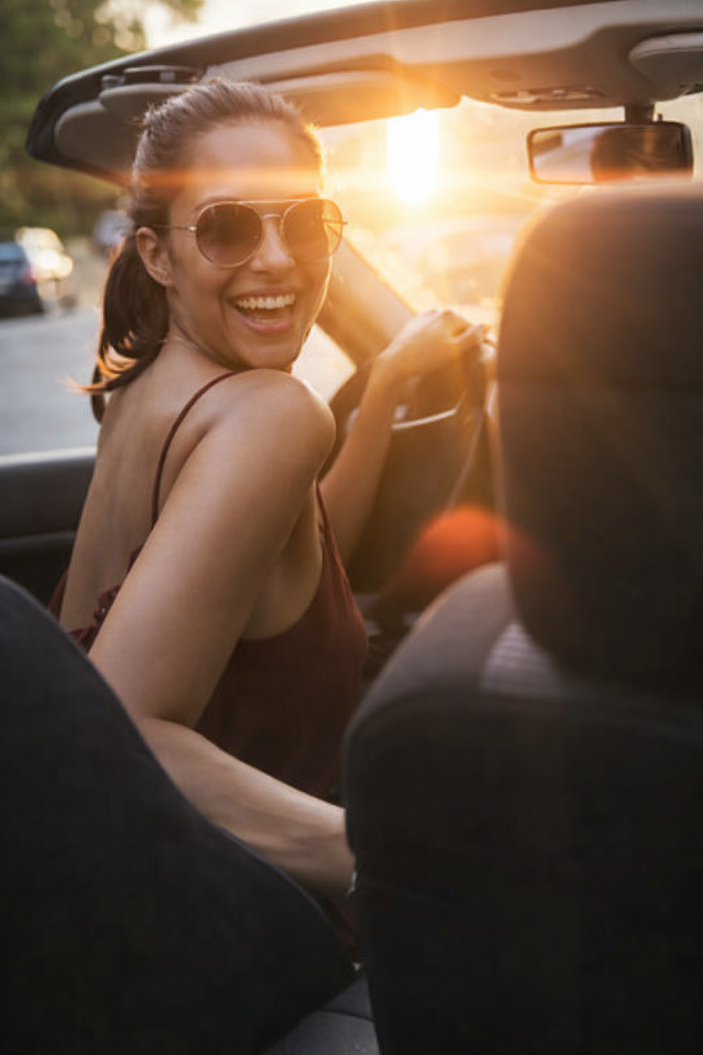 Donna alla guida di una cabrio al tramonto